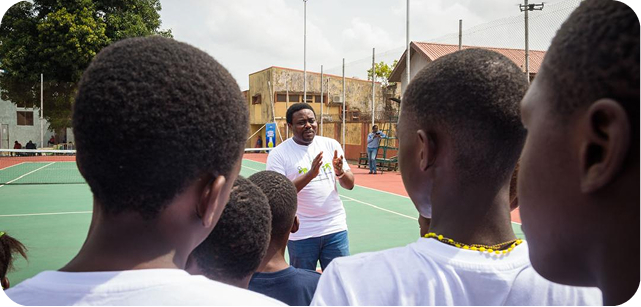 A coach speaking with children on the court