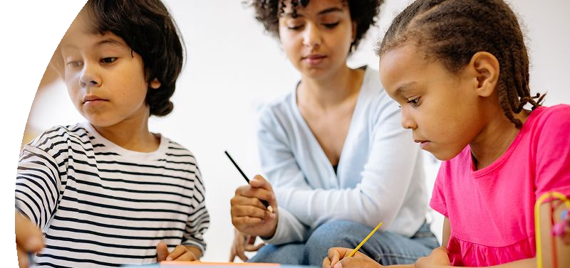 A woman helping two children with their schoolwork