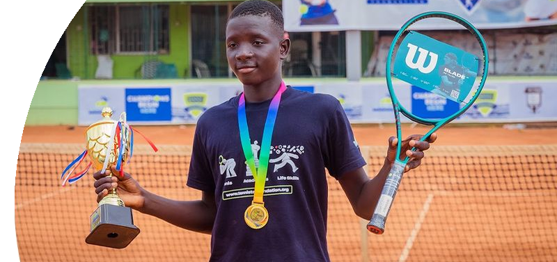A boy holding a trophy and a tennis racket
