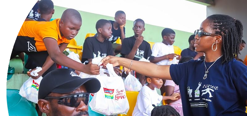 A coach handing supply bags to young players in the stands