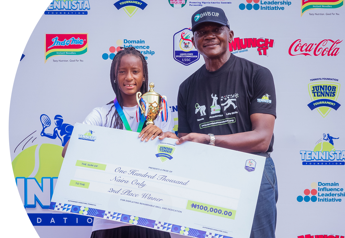 A winner and a coach holding a trophy and a scholarship cheque