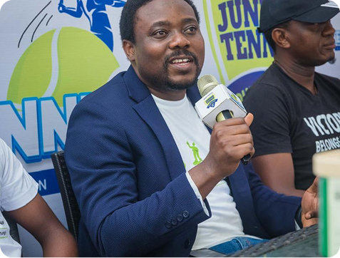 A speaker with a microphone at the Junior Tennis Open
