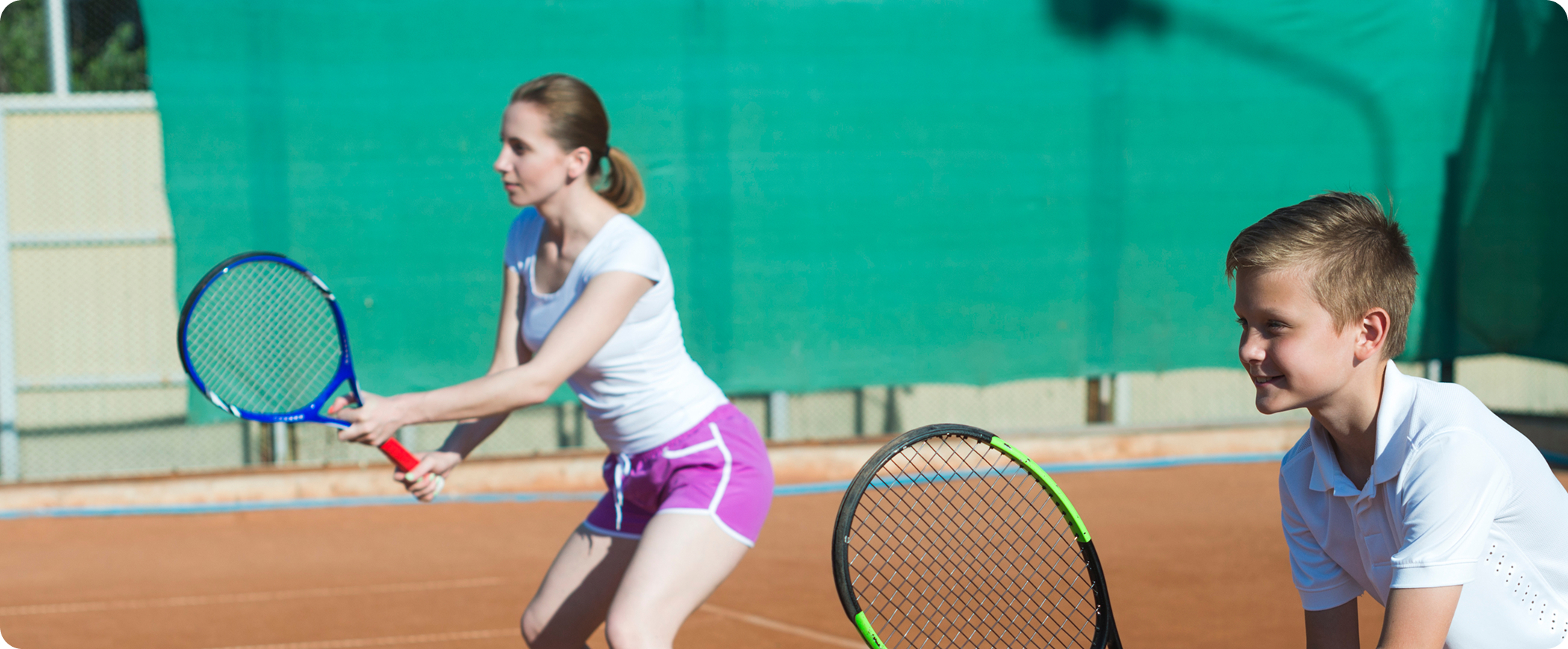 A coach and a young player on a clay court