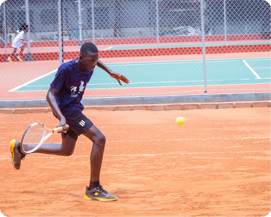 A boy lunging for a ball on a clay court