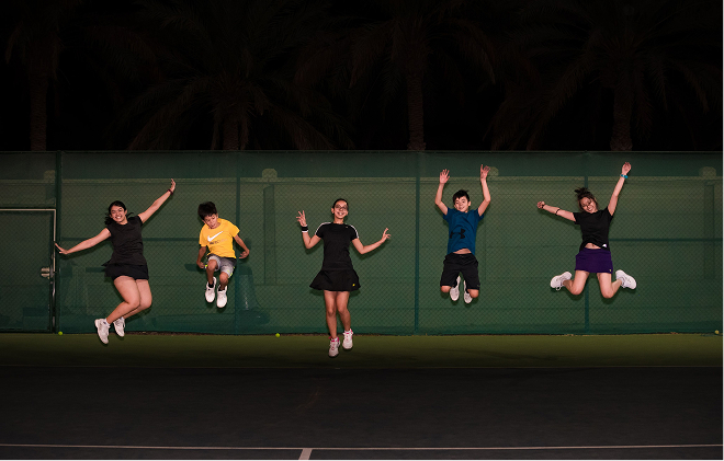 Players jumping in front of a court fence